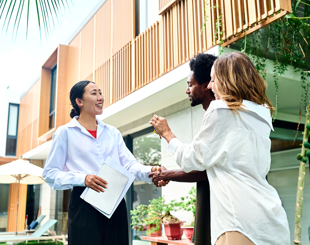 Couple receiving keys and shaking women's hand
